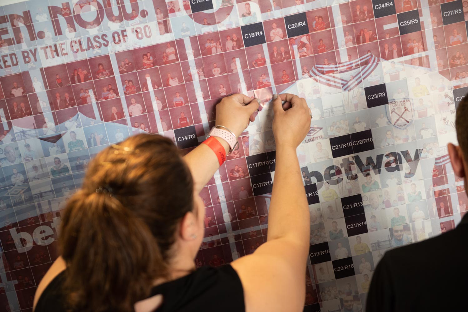Guest placing a photo tile into the West Ham United corporate mosaic wall — photo mosaic wall hire