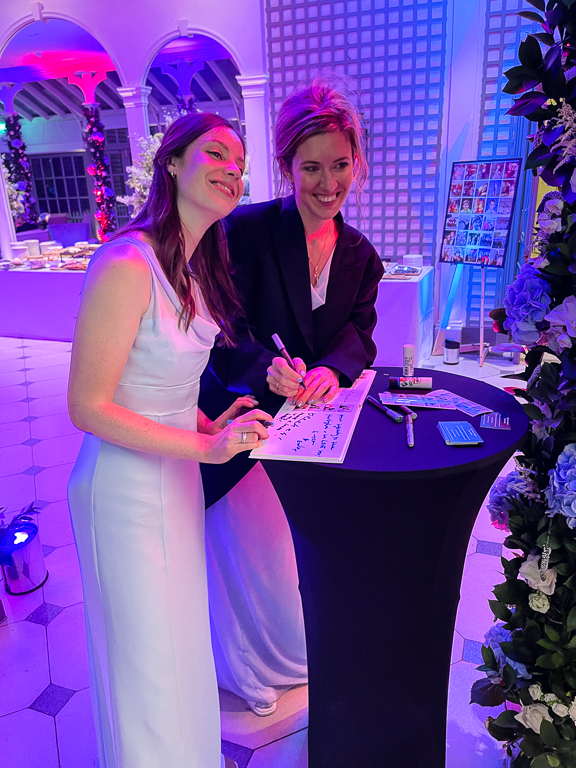 Bride and guest signing a photo booth guestbook at a wedding reception