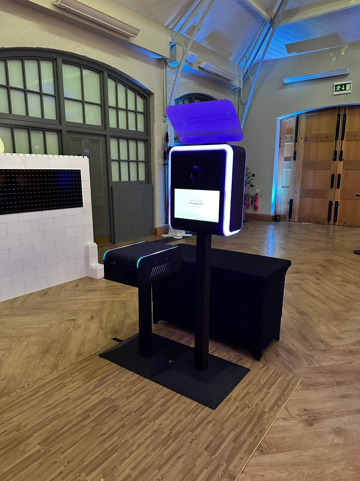 Infinite Selfie Booth with a purple illuminated frame and separate printer in an event hall