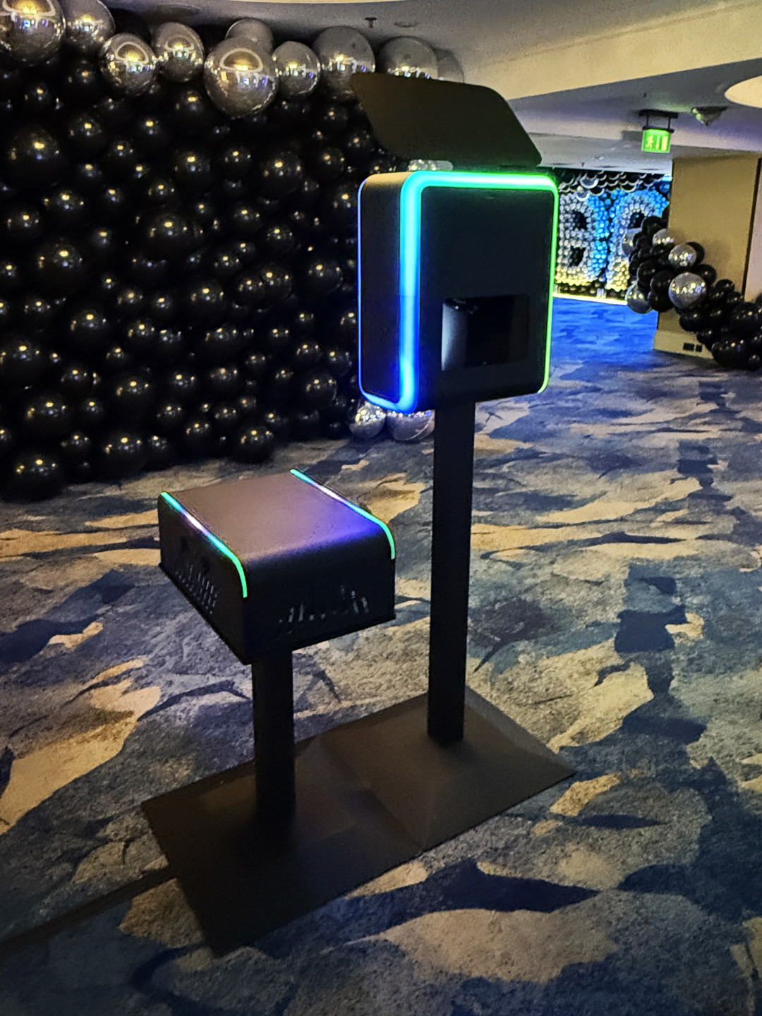 Infinite Selfie Booth with an illuminated frame beside a black and silver balloon wall