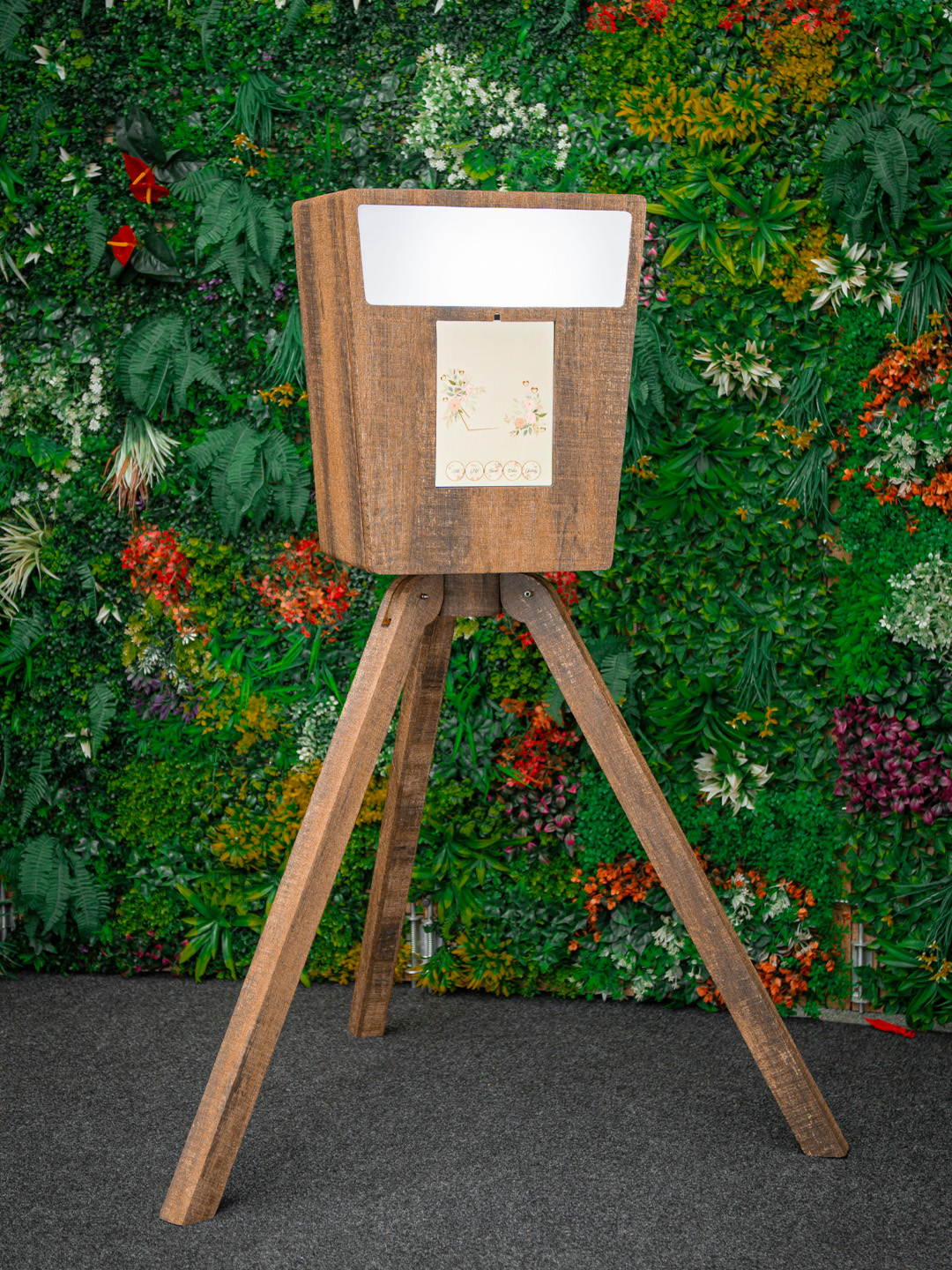 Wooden digital Vintage Booth on a tripod in front of a foliage wall