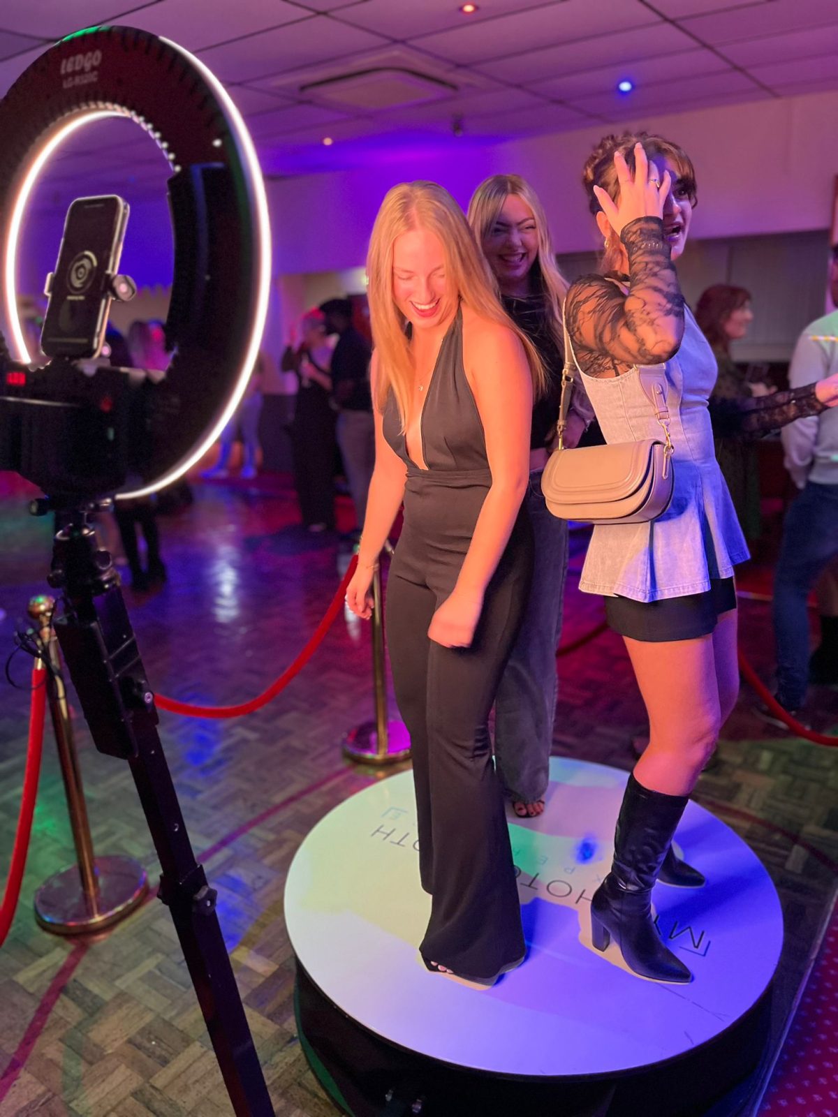 Guests posing on a 360 photo booth platform at an evening celebration