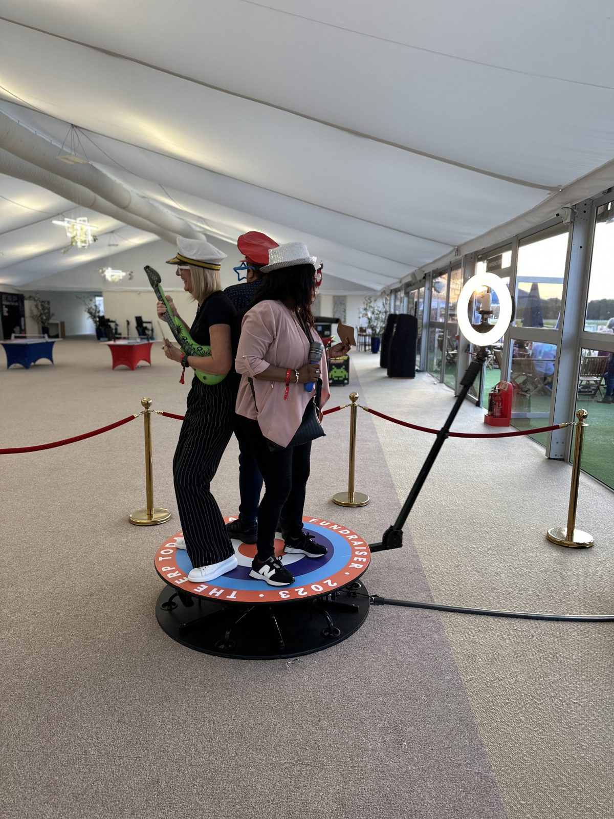Guests posing on a 360 photo booth platform beside a camera arm