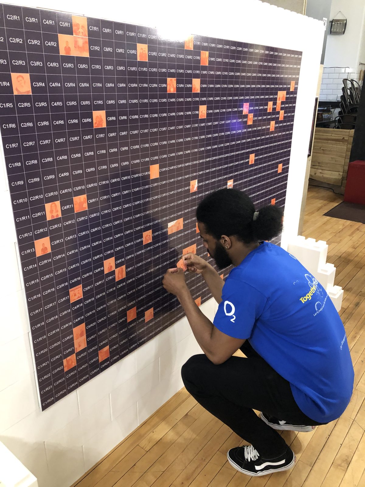 Participant placing a photo tile on a branded mosaic wall