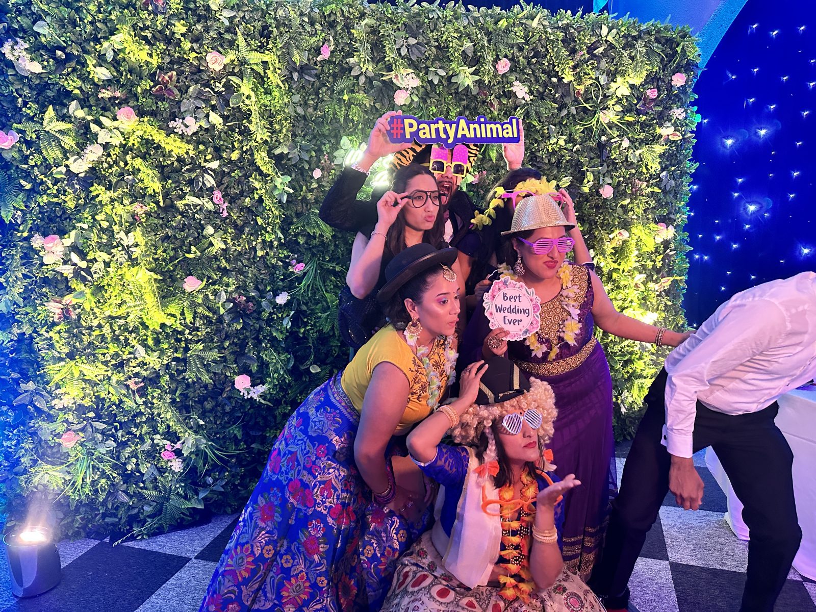 Party guests posing with signs in front of a foliage photo backdrop