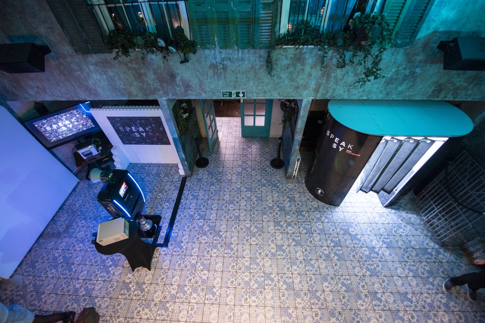 Speak Easy branded photo booth and mosaic wall in an indoor event courtyard