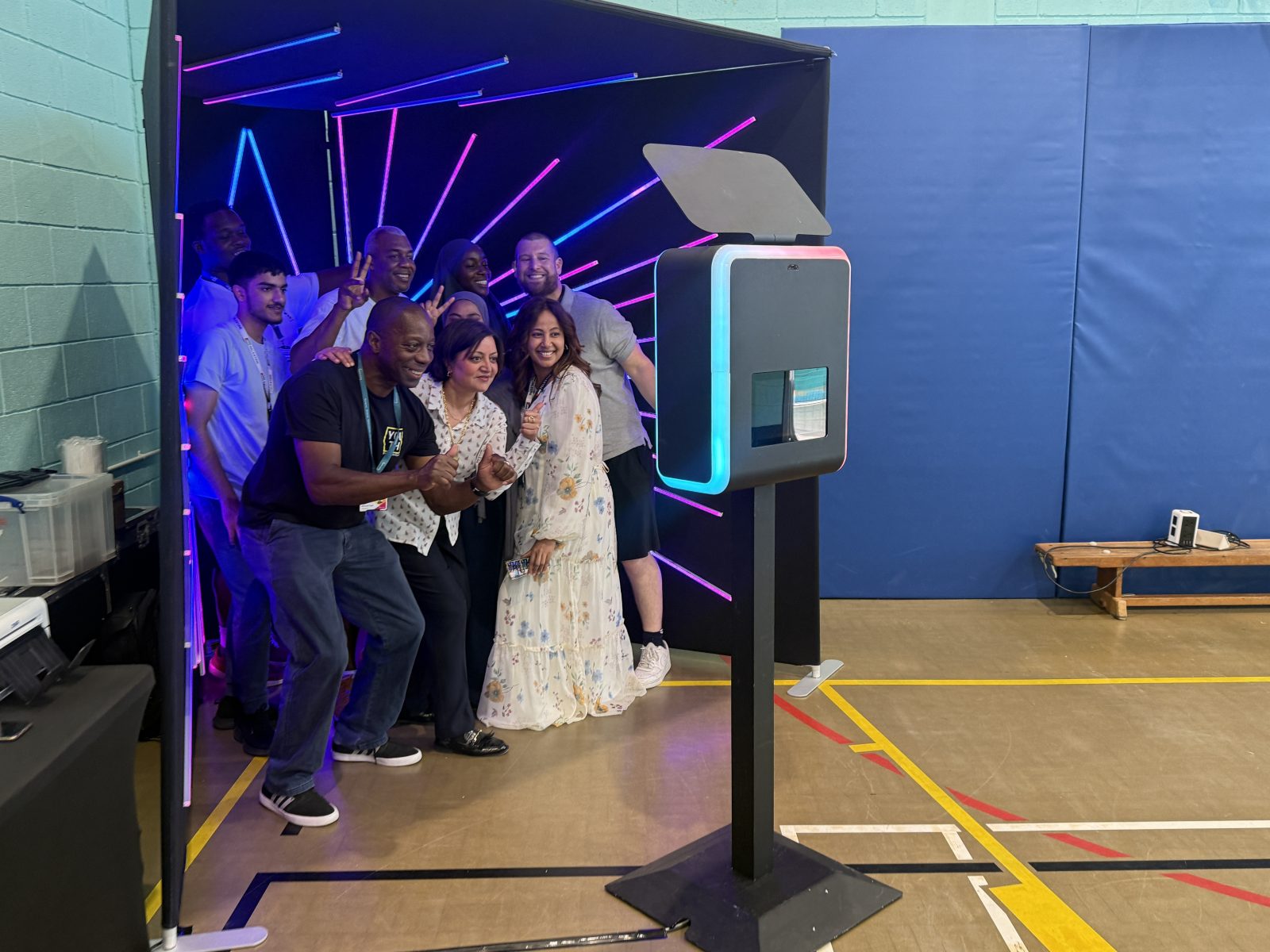 Wedding guests gathered beside a digital booth and turquoise LED backdrop