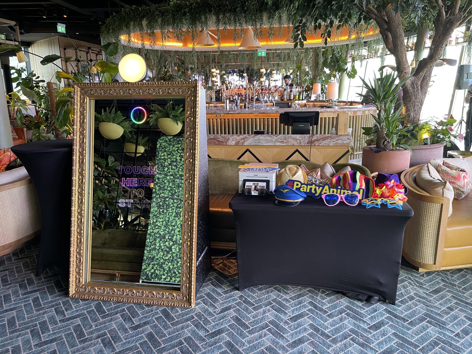 Wood-finish digital wedding photo booth beside a foliage backdrop